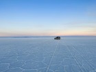 乾季の真っ白なウユニ塩湖を走る4WD。