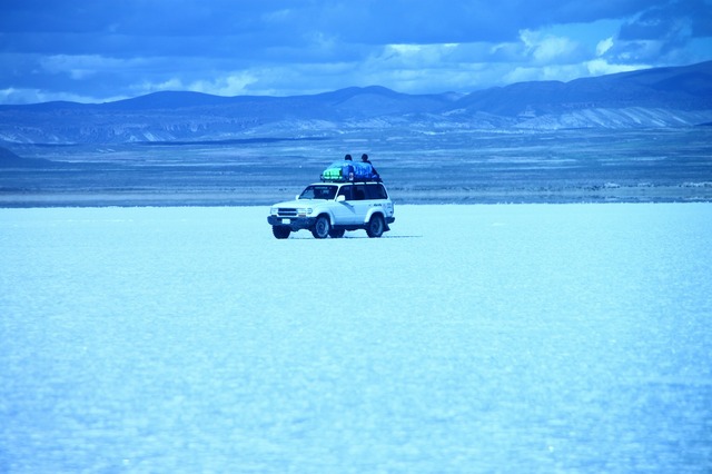 乾季の真っ白なウユニ塩湖を走る4WD。