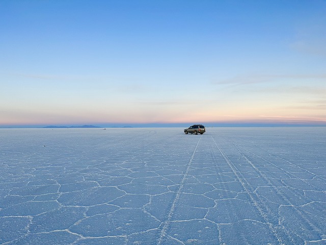 乾季の真っ白なウユニ塩湖を走る4WD。